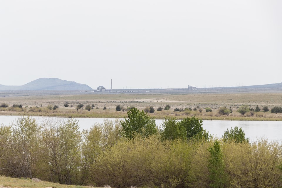 Color photograph of a waterfront area. Across the distance is a broad expanse of land w/ buildings