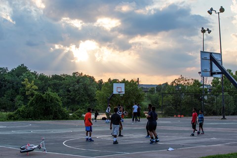 Several people play basektball at sunset in Anacostia Park