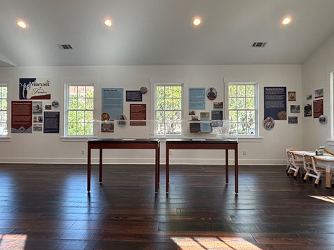 A room with several windows, and red, white, and blue exhibit panels on the walls.