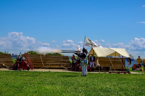 A group of living historians firing muskets on a sunny day in War of 1812 kit.