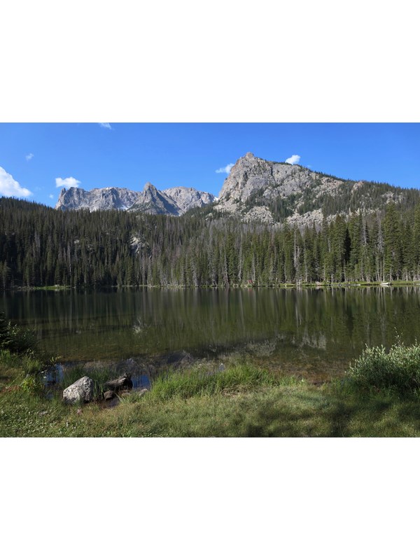 tree lined lake with a mountain backdrop