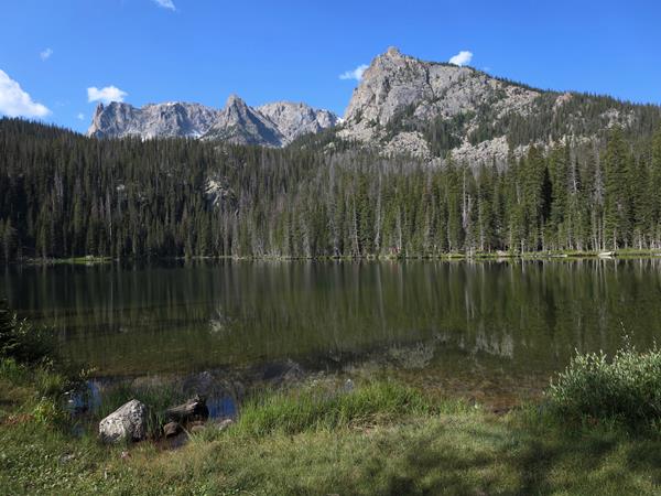 tree lined lake with a mountain backdrop