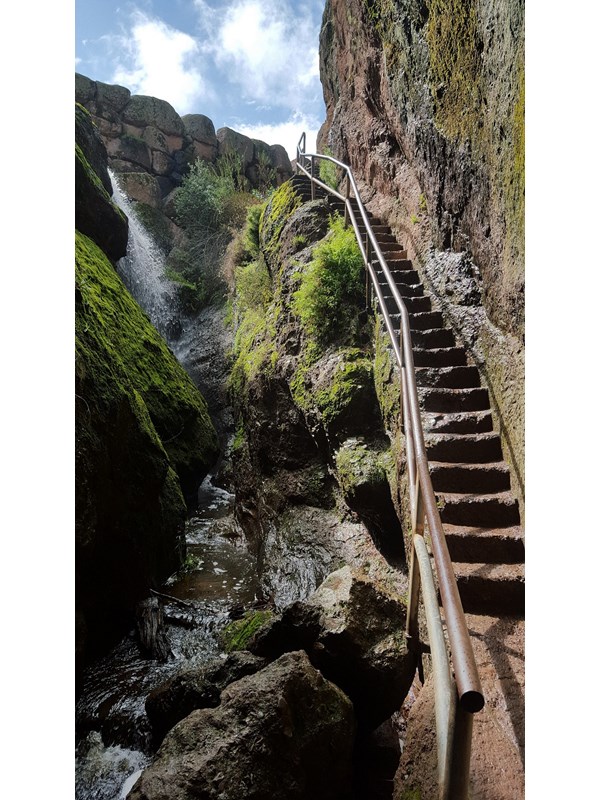 Narrow rock staircase edged out of rock wall in a narrow rock canyon