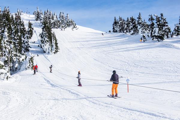 Skiers on a rope tow on a snowy slope.