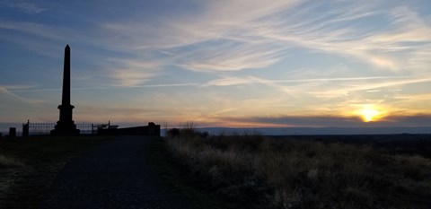 Silhouette of a monument and open field set against the sunset