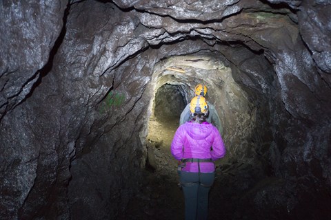 Two people walking underground in a small tunnel