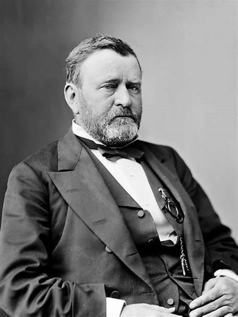 Bearded man wearing black and white suit with bow tie.