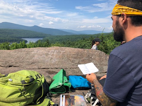A man before a mountain vista looks over a map.