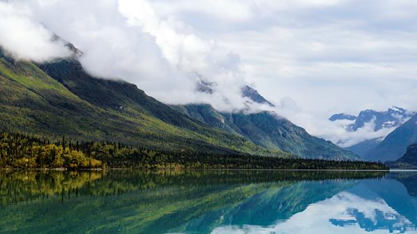 Mountains and yellow trees reflect in blue waters