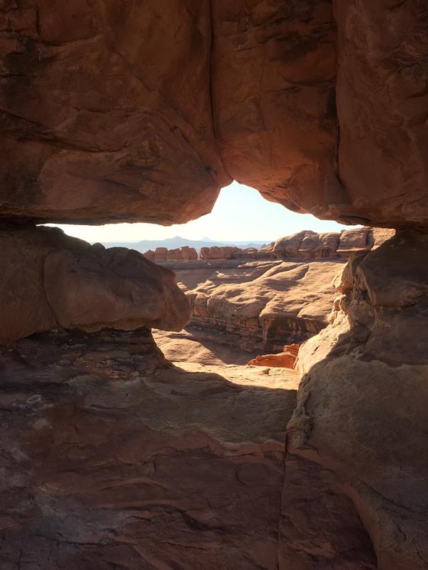Canyons seen through a small opening along a sandstone wall