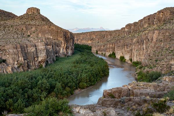 A wide river curves through a canyon with high limestone walls.