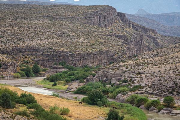 A river crosses an open plain before heading into a limestone canyon.
