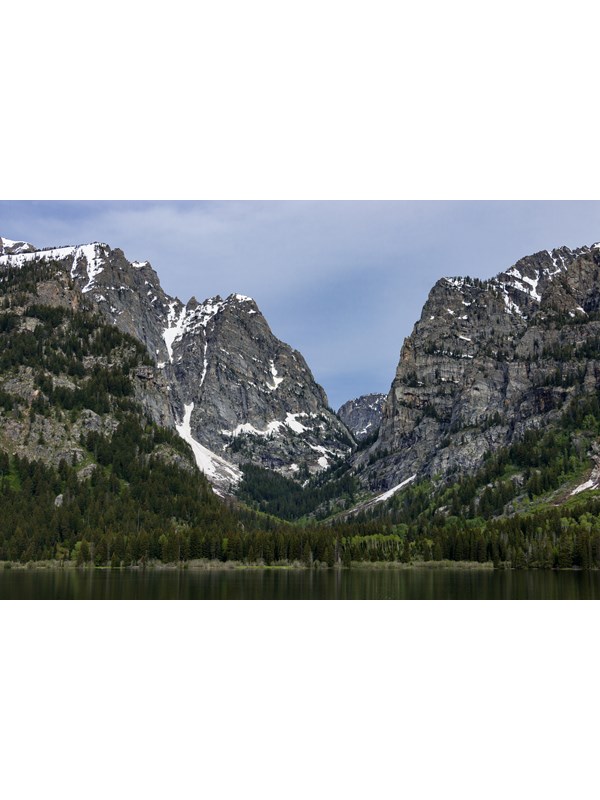 A rocky, mountain canyon sits across a calm lake.