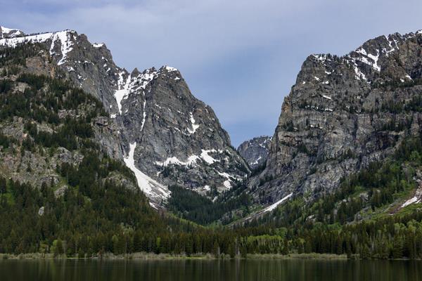A rocky, mountain canyon sits across a calm lake.