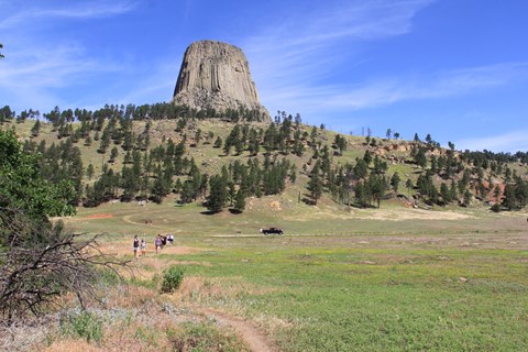 people walking along a dirt path through the prairie dog town, Devils Tower in the background