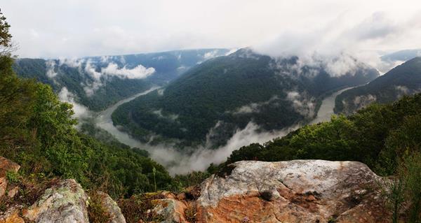 a view into a deep river gorge with clouds