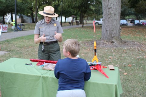 Female ranger talking to a young boy with a table between them