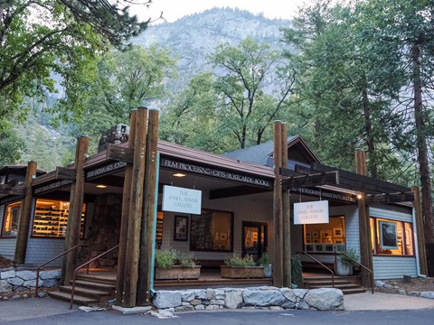 A covered porch with exposed log beams leads to a warmly lit rustic building