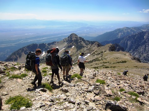 Four hikers walk down a steep, rocky trail.