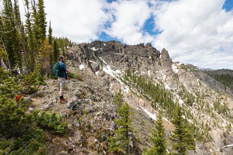 A hiker takes in the views approaching a rocky summit.