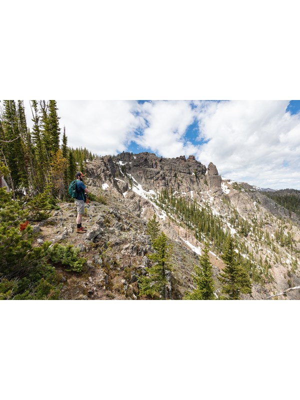A hiker takes in the views approaching a rocky summit.