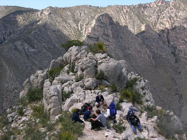 A group of hikers relax along a trail high up on a mountain