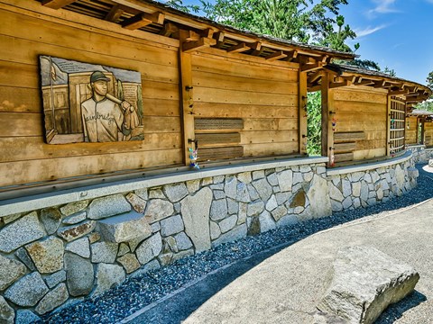 Wooden panels above stone wall along a paved walkway.