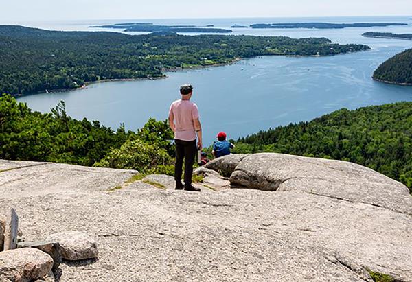 Visitors overlook islands from a mountain summit.