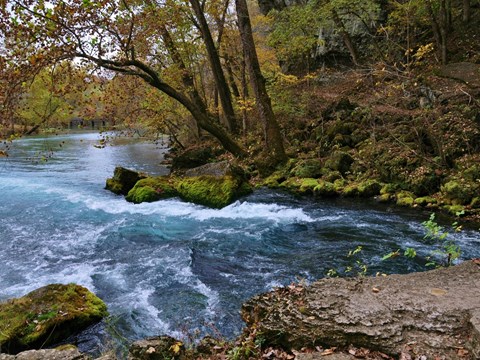 Big Spring with clear blue water flowing, and rocks covered with moss and trees lining spring