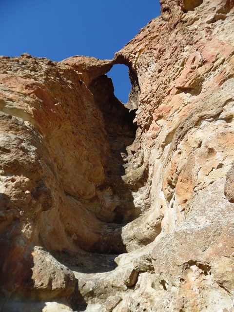 A small rock arch at the top of a cliffside formed from erosion