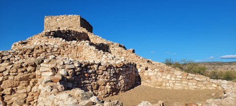 remains of a hilltop dwelling with walls creating square shaped rooms and a tall, central tower