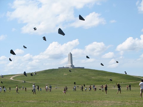 Visitors are scattered across the big green field in front of the monument