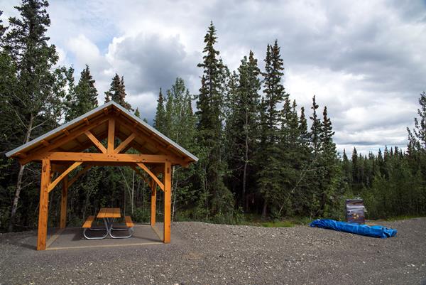 a large shelter covering several picnic tables near spruce trees