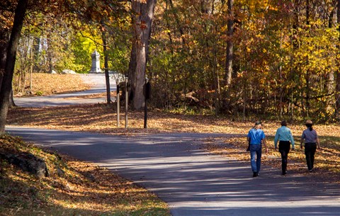 A park ranger with two visitors walking on the driving tour path at Culps Hill