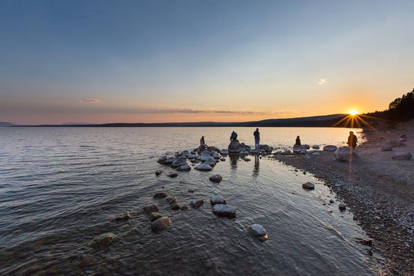 People enjoy the sunset from the shore of Yellowstone Lake.