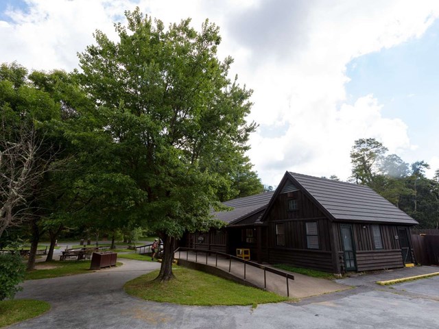 A photograph of a brown building with a walkway in the front and picnic tables outside.