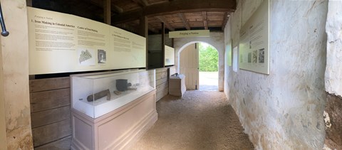 a space inside an historic stable with dirt floor artifact cases and exhibit panels