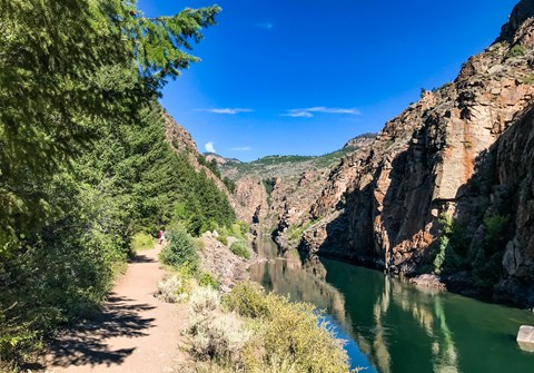 A footpath along a narrow canyon with water and trees