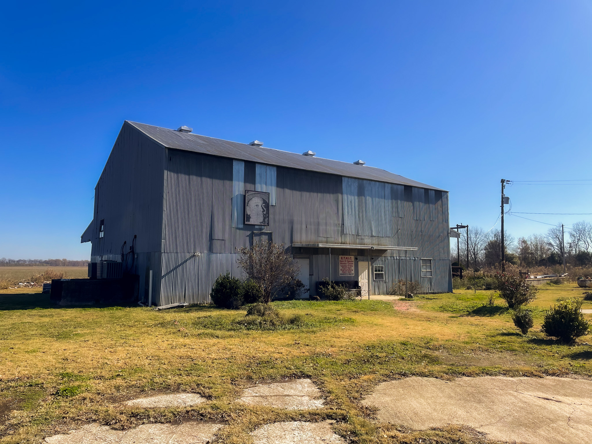A metal cotton gin building sits in an open field