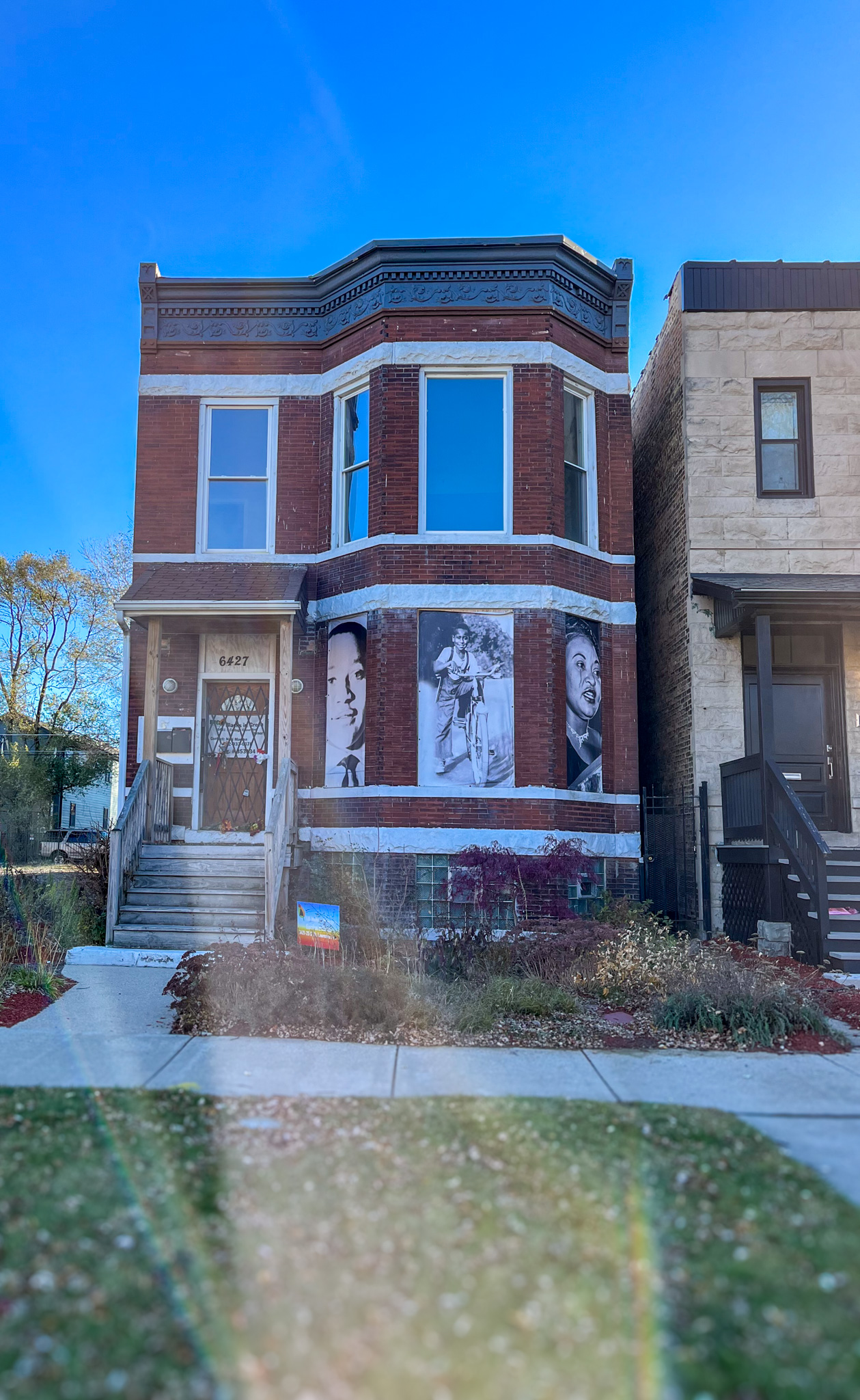 Exterior of a brick residential building with larhe black anmd white photos in the front windows