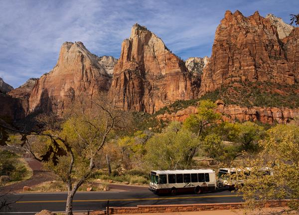 Photo of three large sandstone mountains above a shuttle bus.