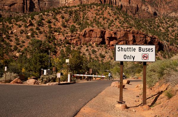 Photo of a road with a gate across it and a sign that reads "Shuttle Buses Only"