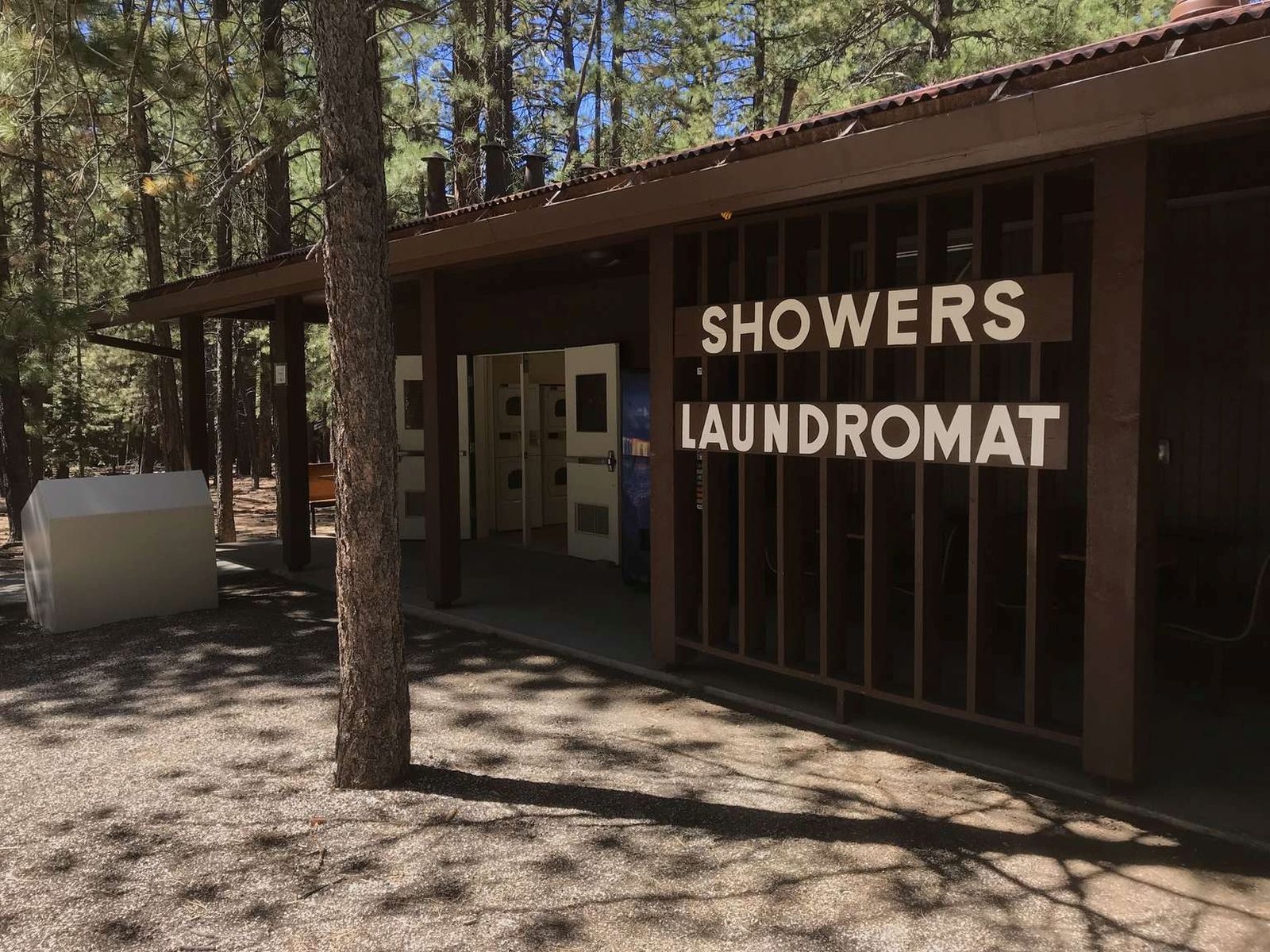 A single story brown wooden building with large white letters reads: "Showers, Laundromat"