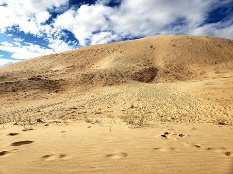 Sand dunes under a cloudy blue sky