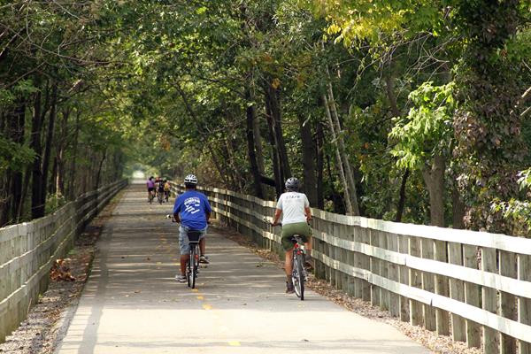 Ranger and visitors ride down the wide paved bike path.