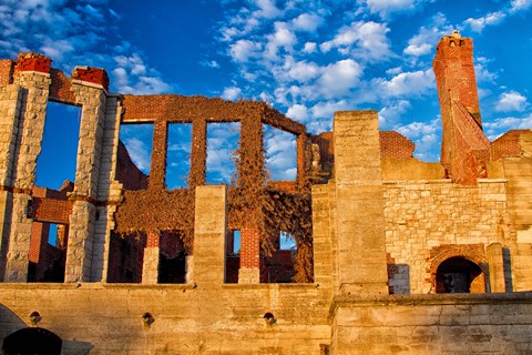 Burnt out ruins of a brick and stone mansion. The blue sky can be seen through empty window frames.