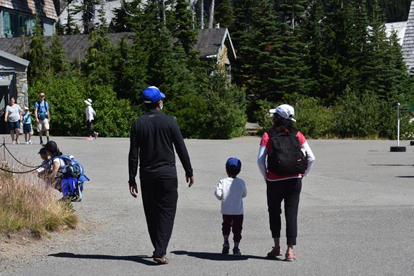 Two adults walking with a child between them on a paved pathway.