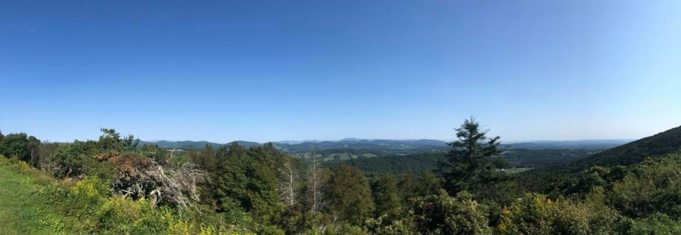 An open overlook with a valley below and mountain ridges in the distance
