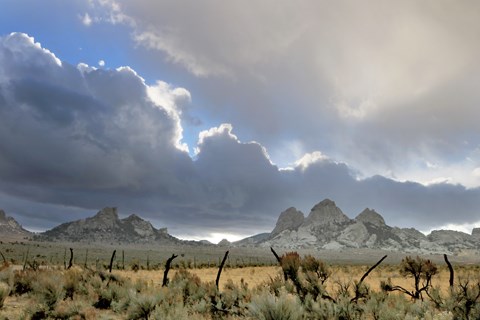 Two rocky hills in the distance with a visible pass in between them. Spectacular cloudy sunset.