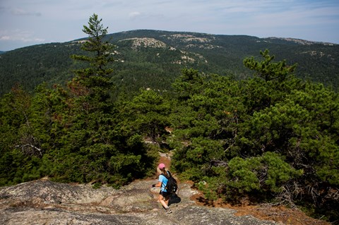 Visitor hikes down exposed granite section of trail